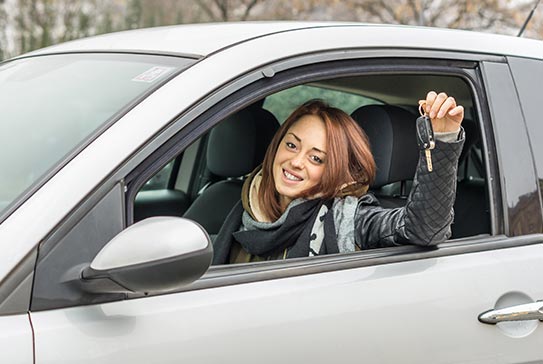 Jeune femme au volant d'une voiture montrant ses clés
